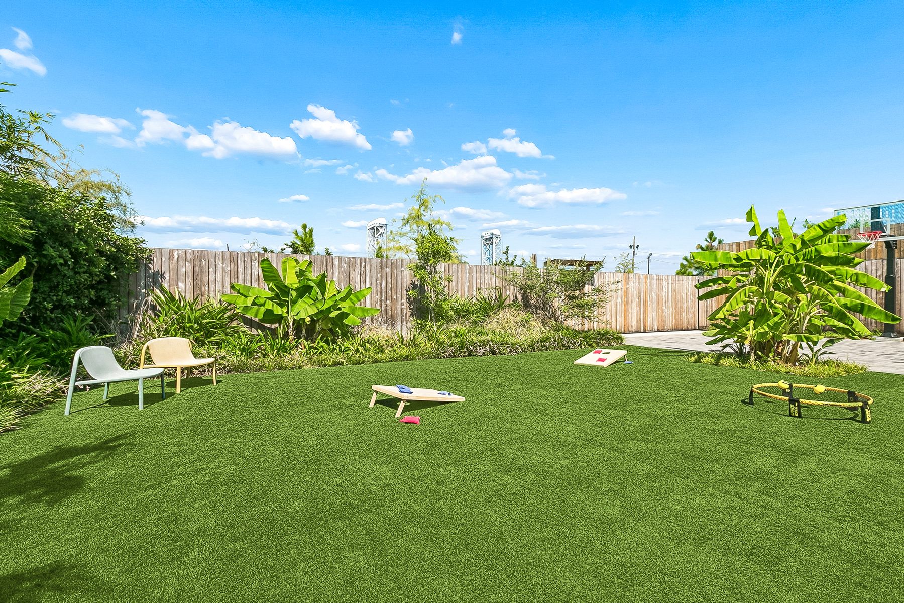 The turf lawn with cornhole boards, a spikeball set, and two chairs