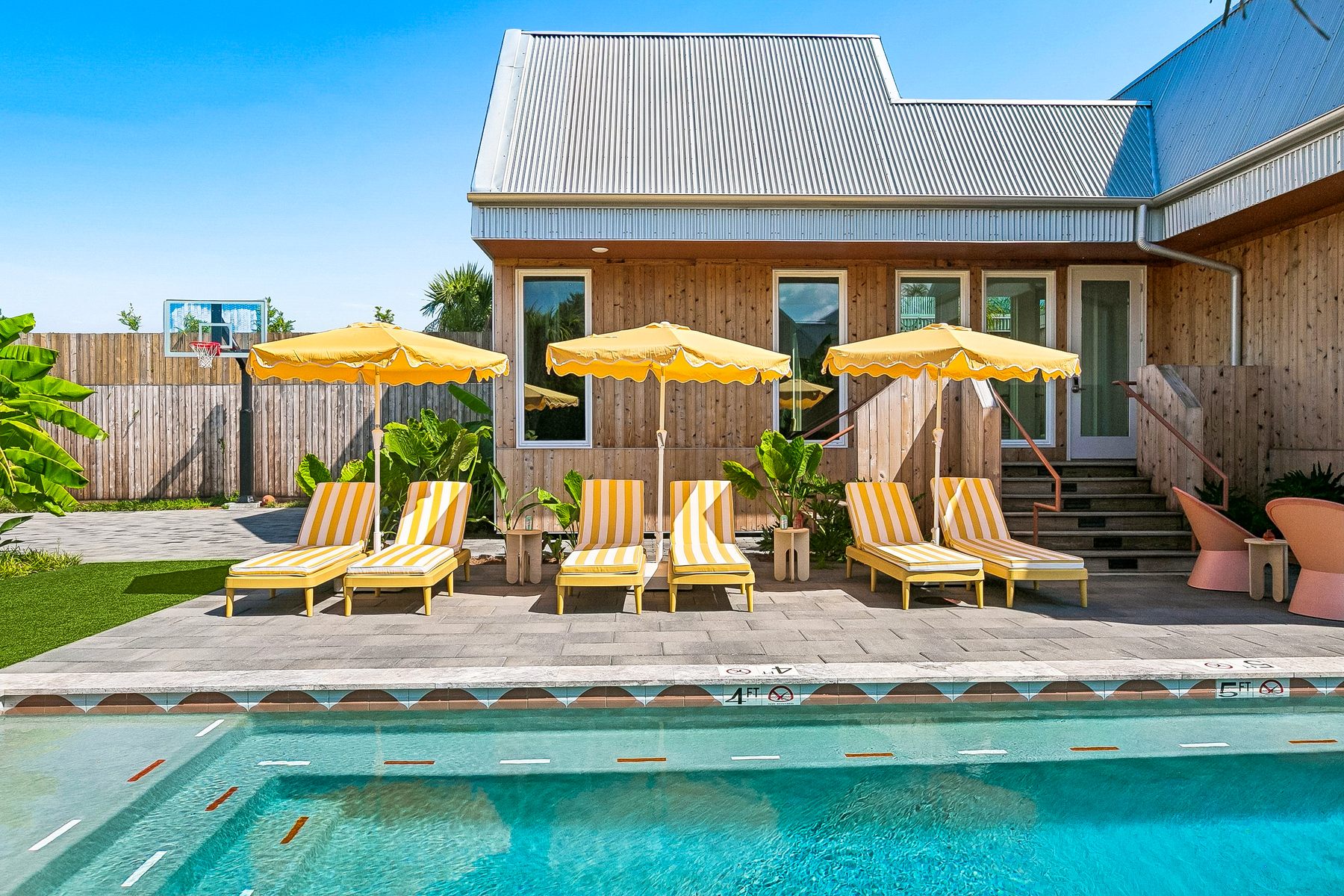 The heated pool and a row of striped loungers under yellow umbrellas