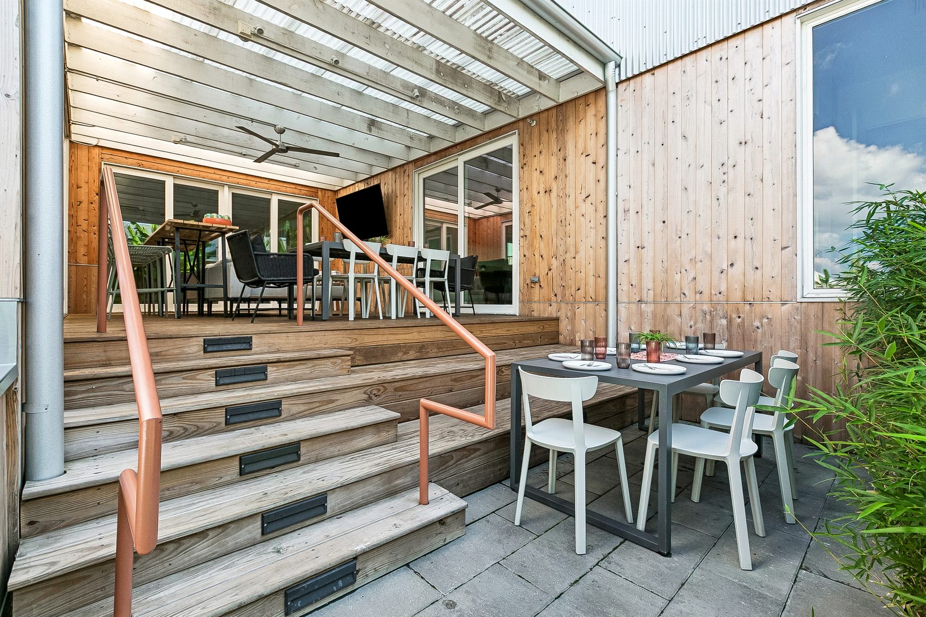 Dining tables at the foot of the steps and under the covered patio